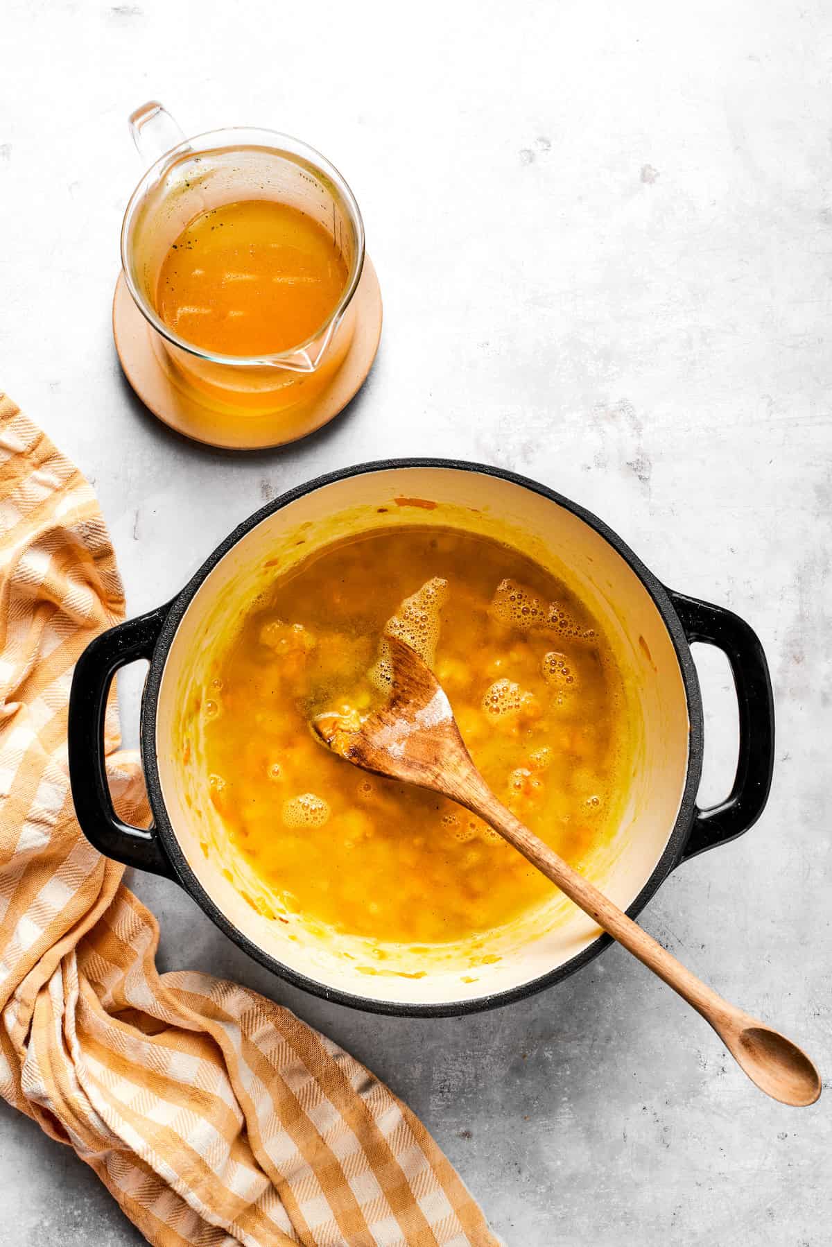 Stirring broth into a pot with carrots and roux.