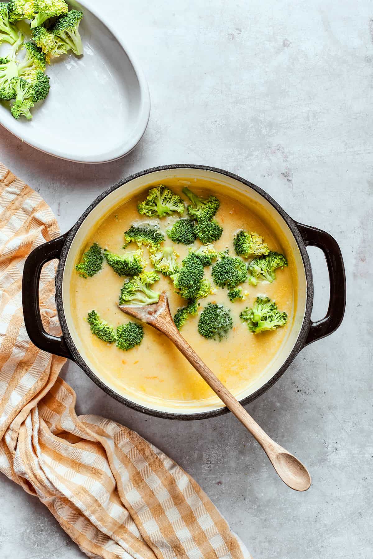 Stirring broccoli florets into a pot of soup.