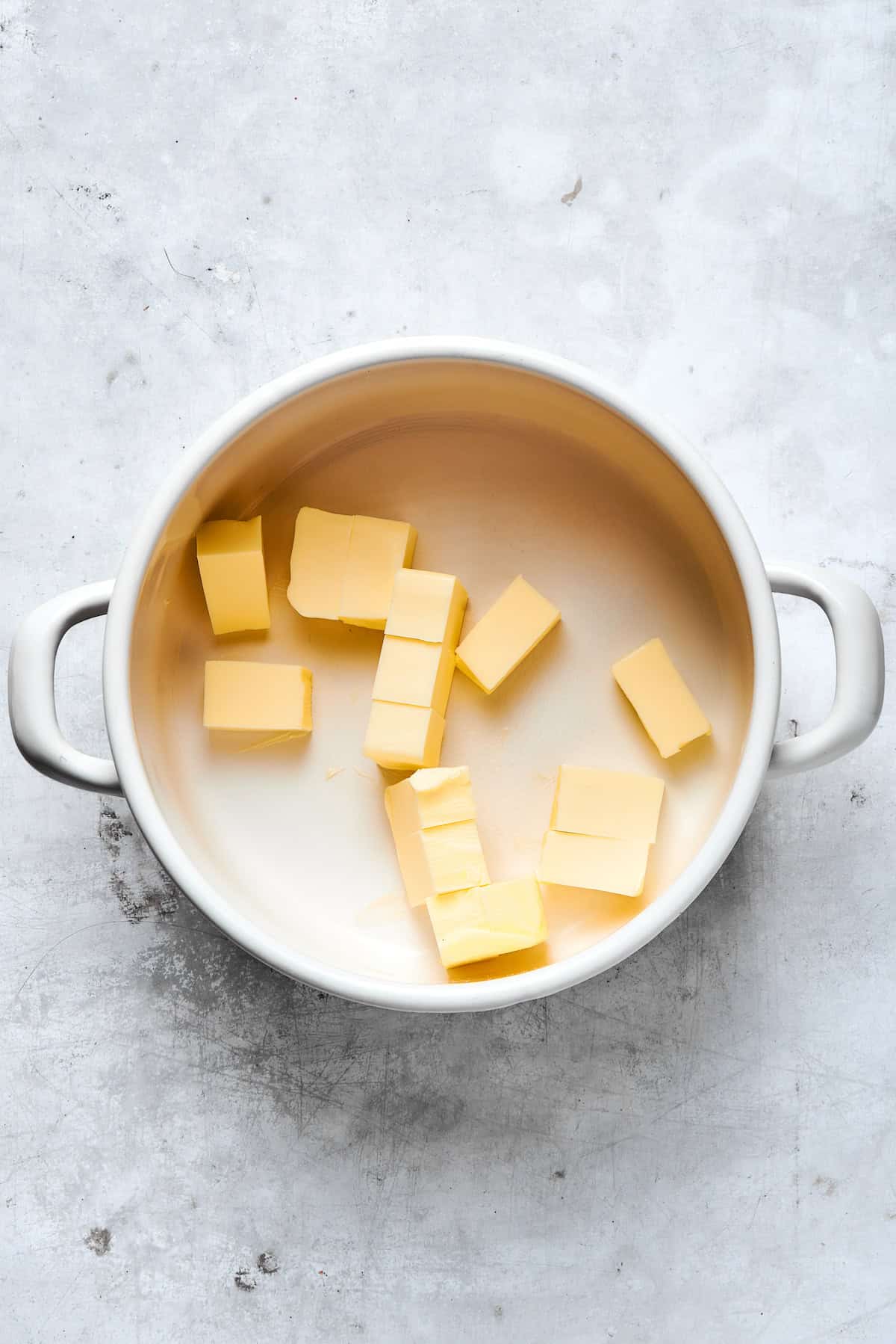 Pieces of butter melt in a pot.