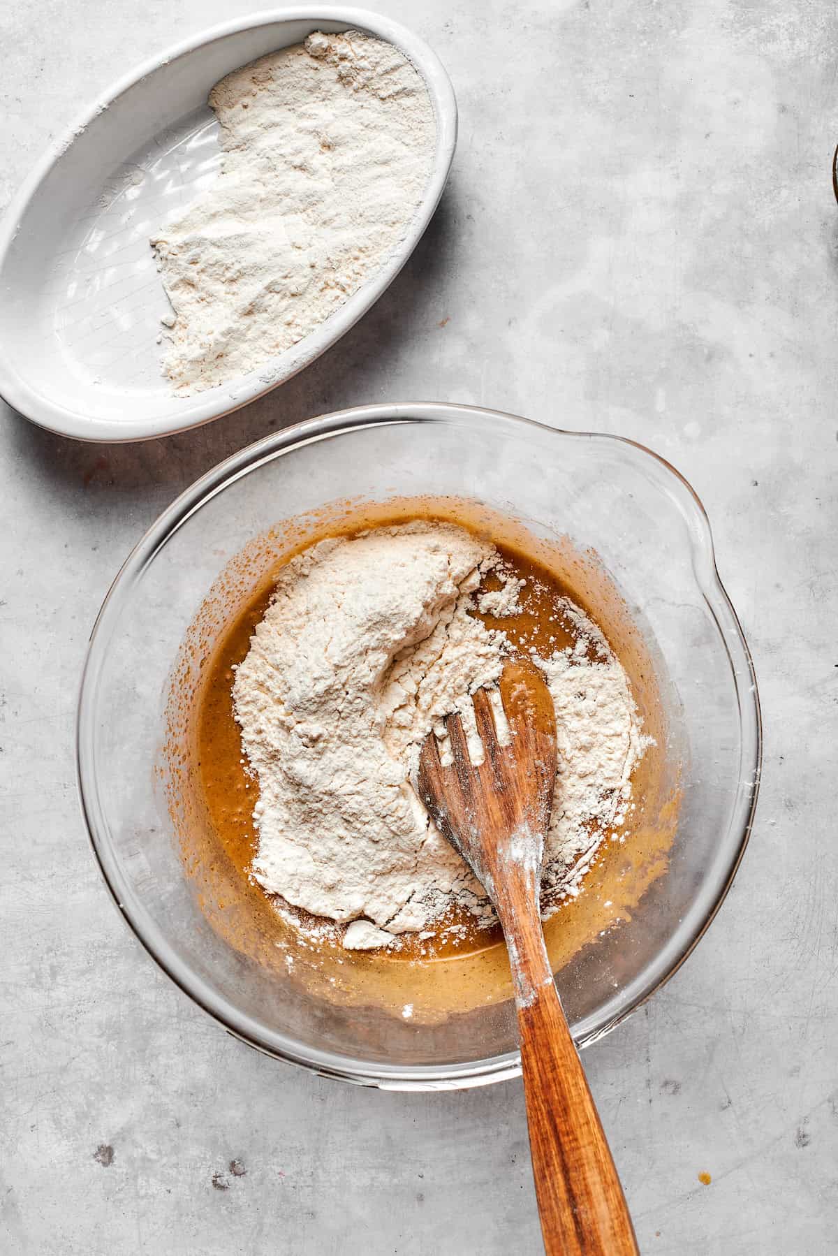 Dry ingredients are mixed into a bowl of cookie dough.