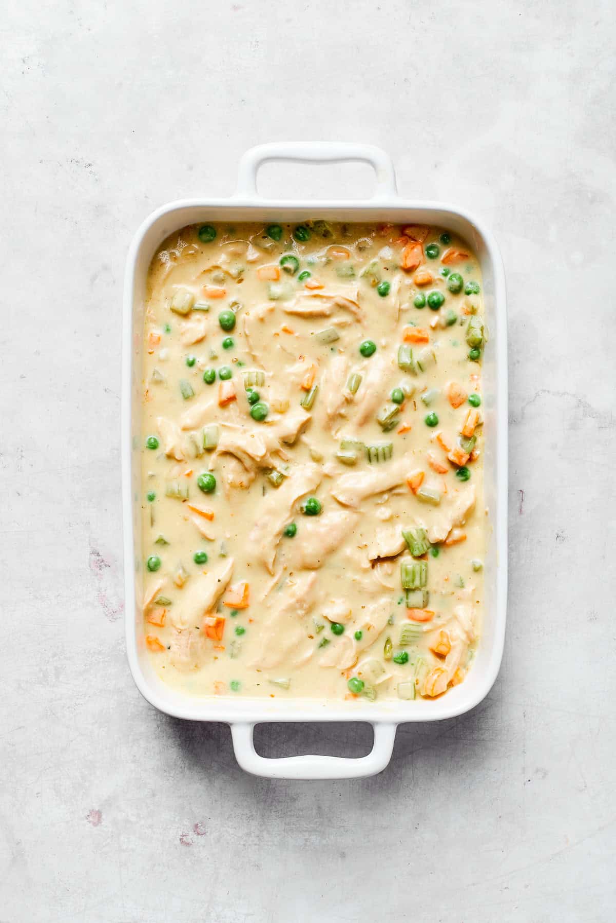 Creaming chicken filling in a baking dish.