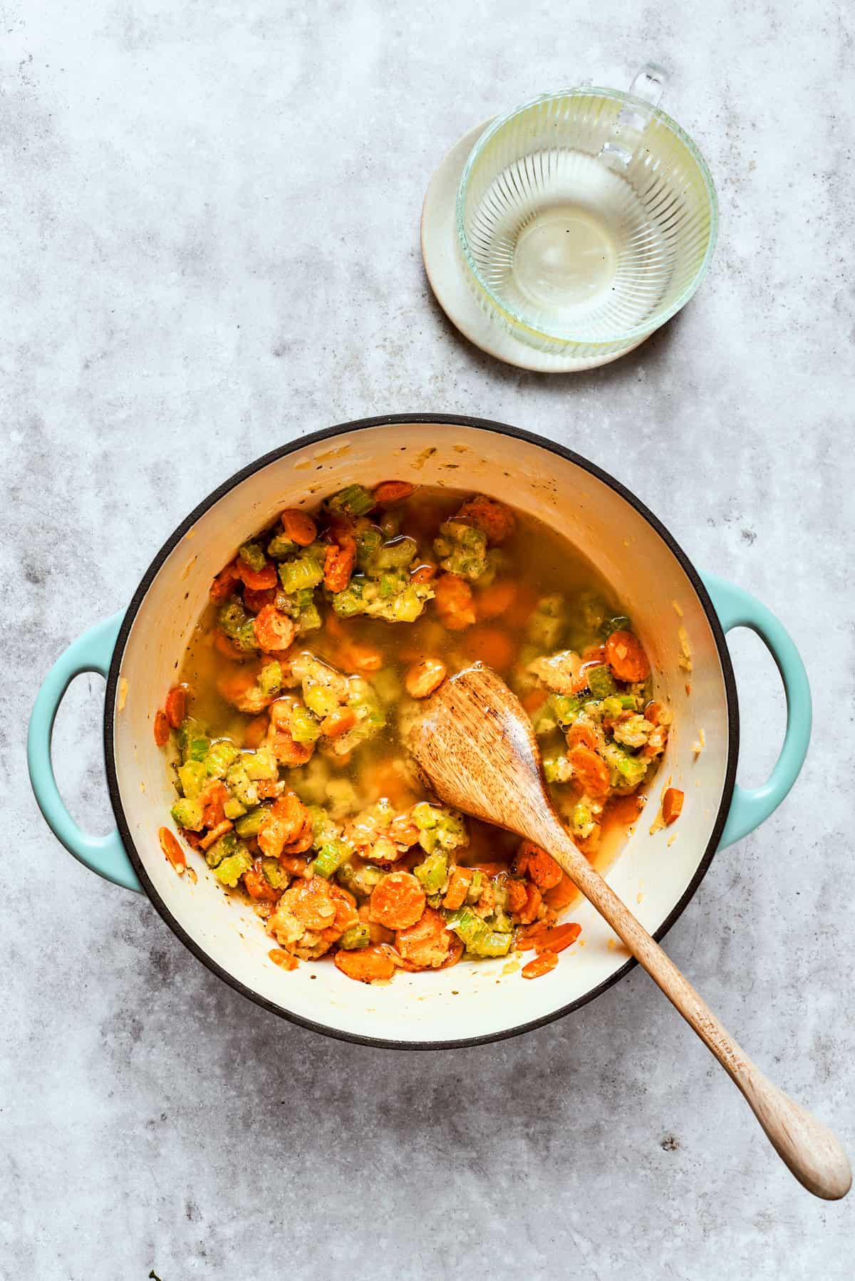 Adding broth to veggies in a large pot. 