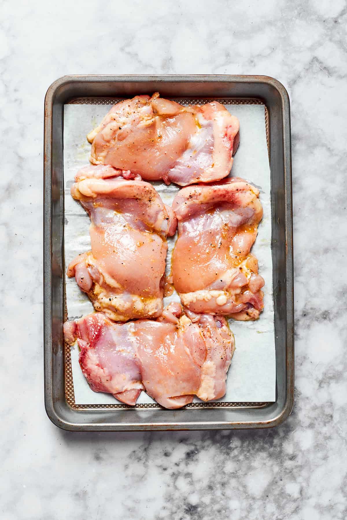 Raw chicken on a baking sheet ready to roast.