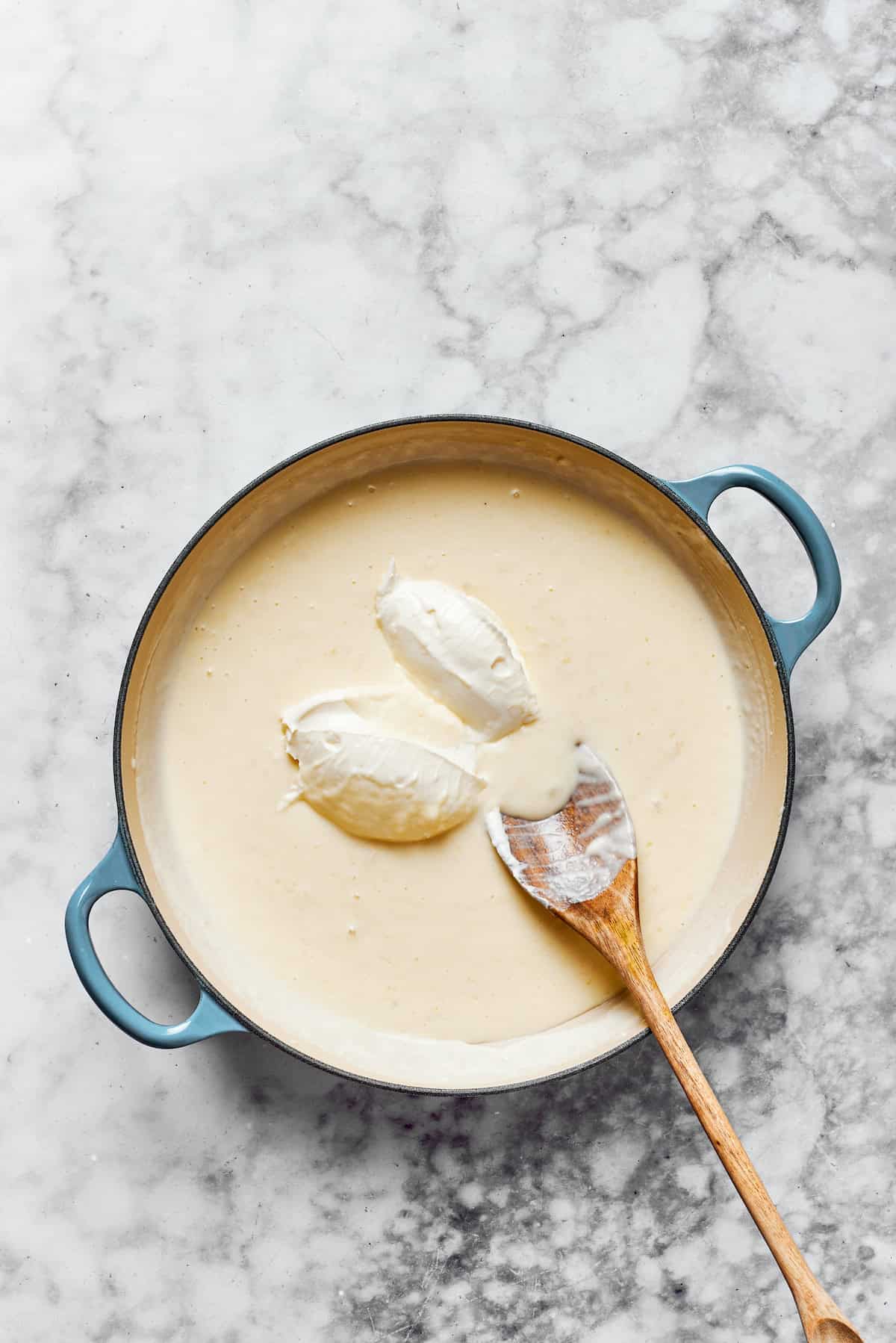 Adding cream cheese to roux in a pan.