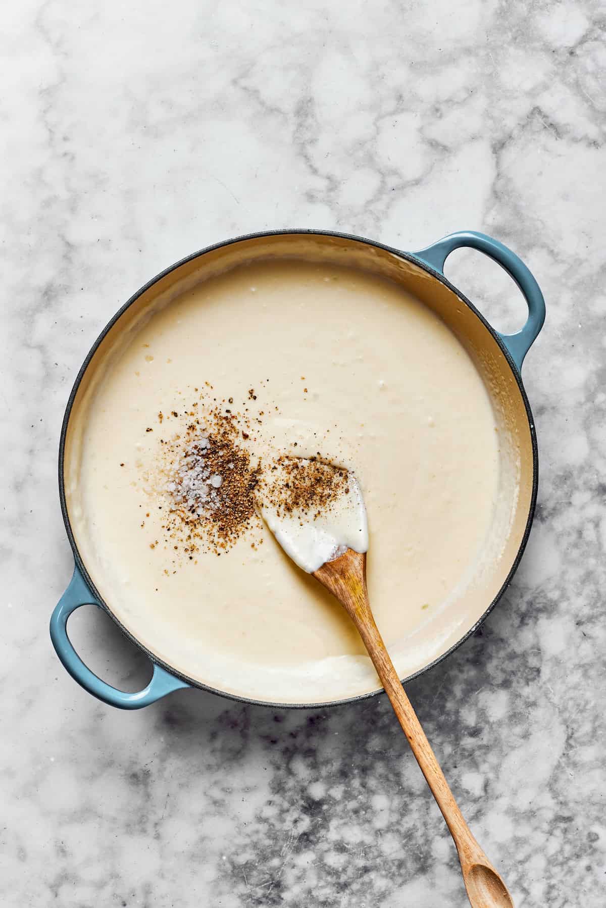 Adding seasonings to a creamy pasta sauce.