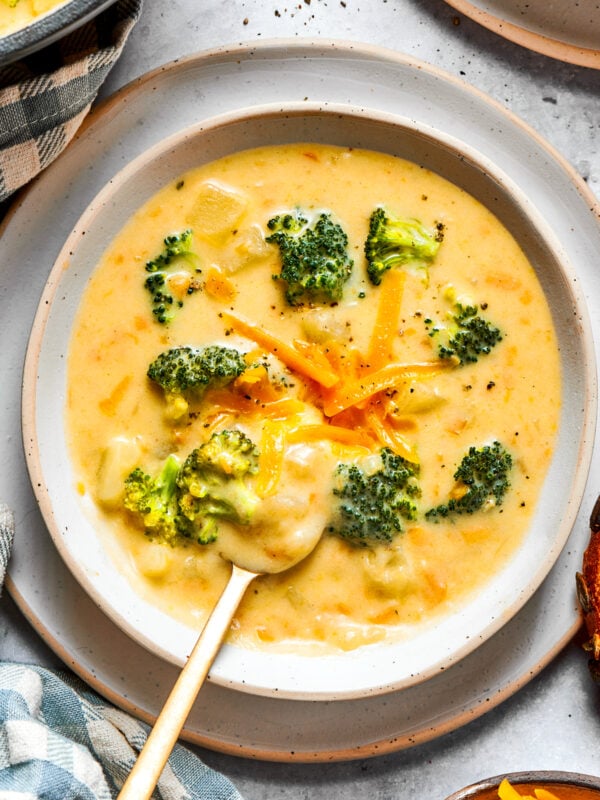 Broccoli cheese soup served in a bowl and garnished with shredded cheese and broccoli florets.