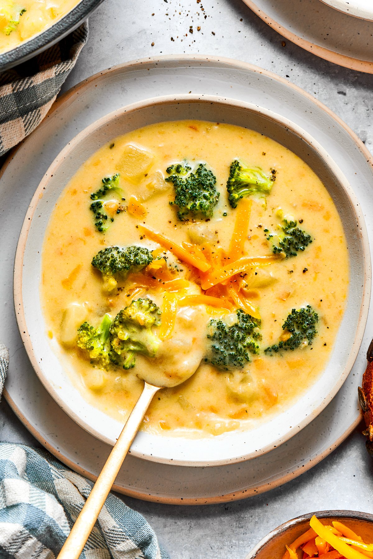 Broccoli cheese soup served in a bowl and garnished with shredded cheese and broccoli florets.