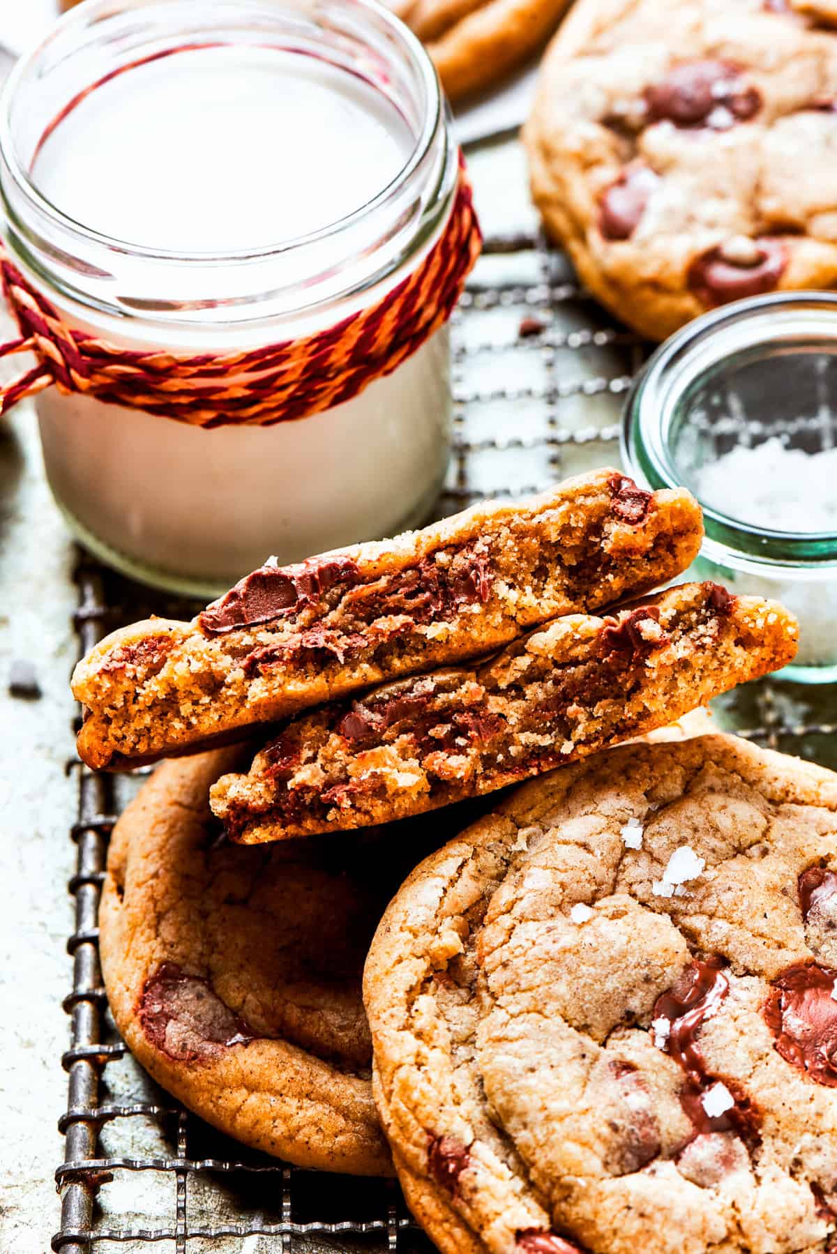 Brown butter chocolate chip cookies on a cooling rack next to a jug of milk.