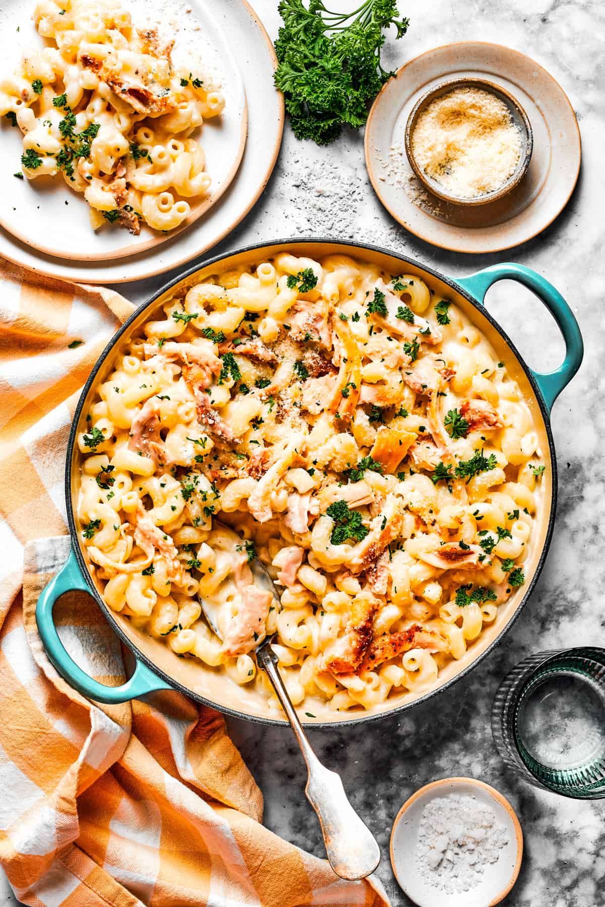 Overhead photo of parmesan chicken pasta in a pot, with a serving of the pasta on a dinner plate set next to the pot.