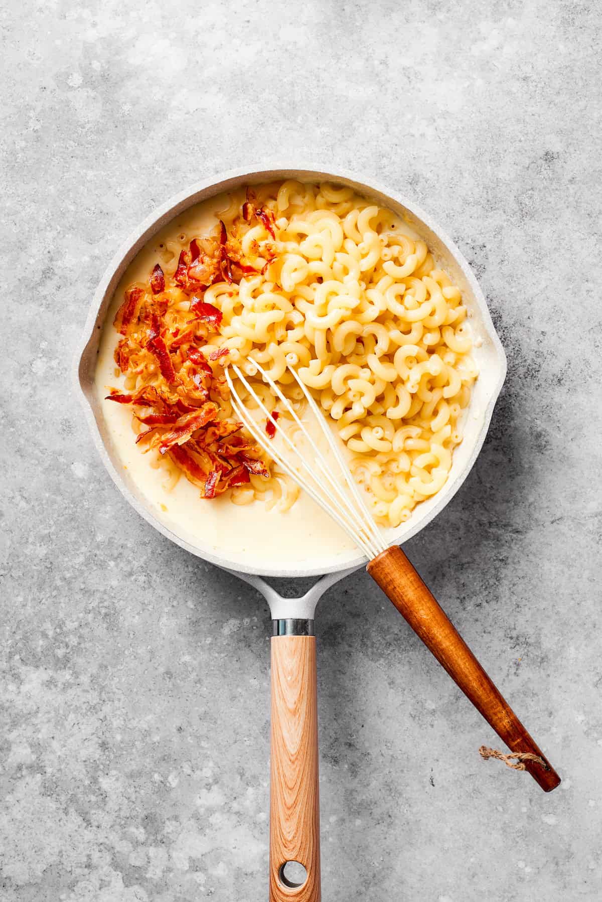 Bacon and pasta is added to a pan of roux.