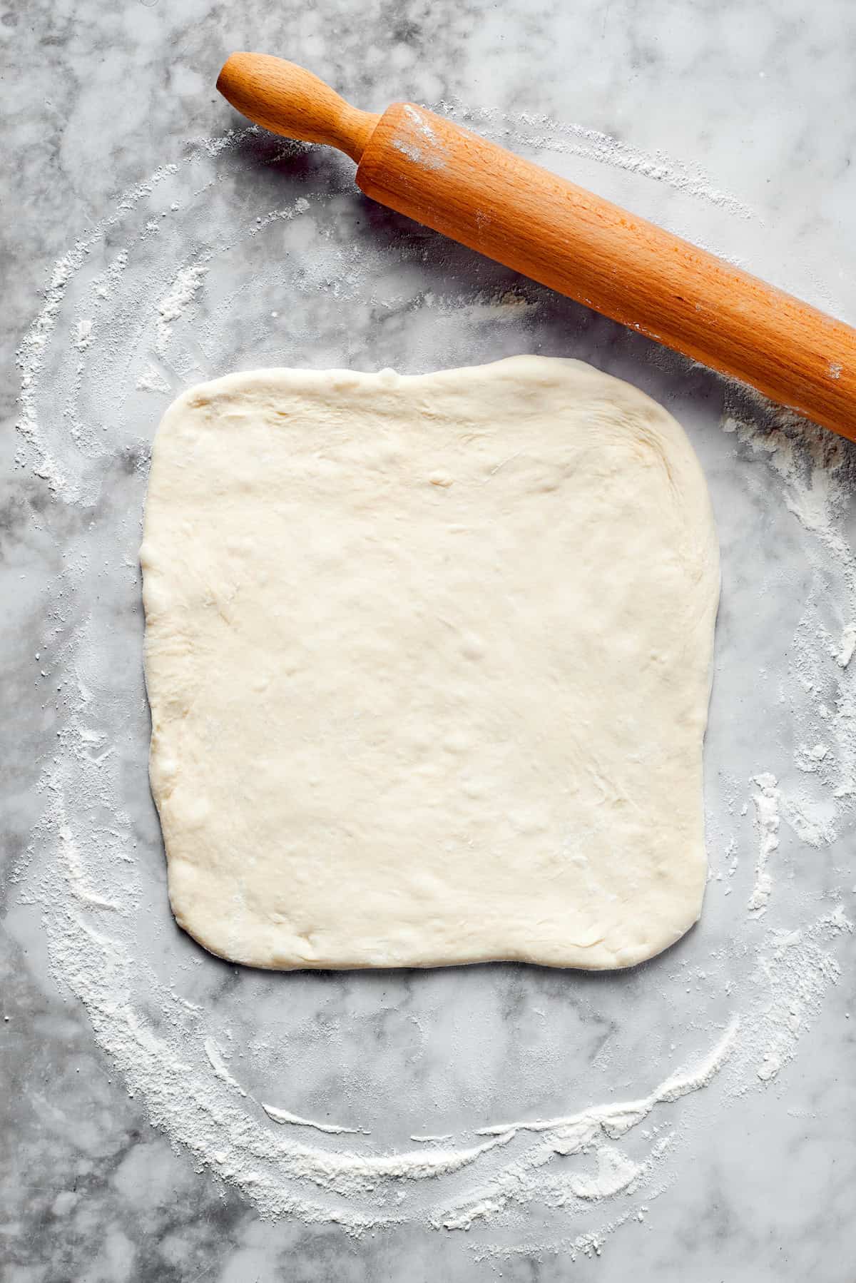 Pizza dough rolled into a square.