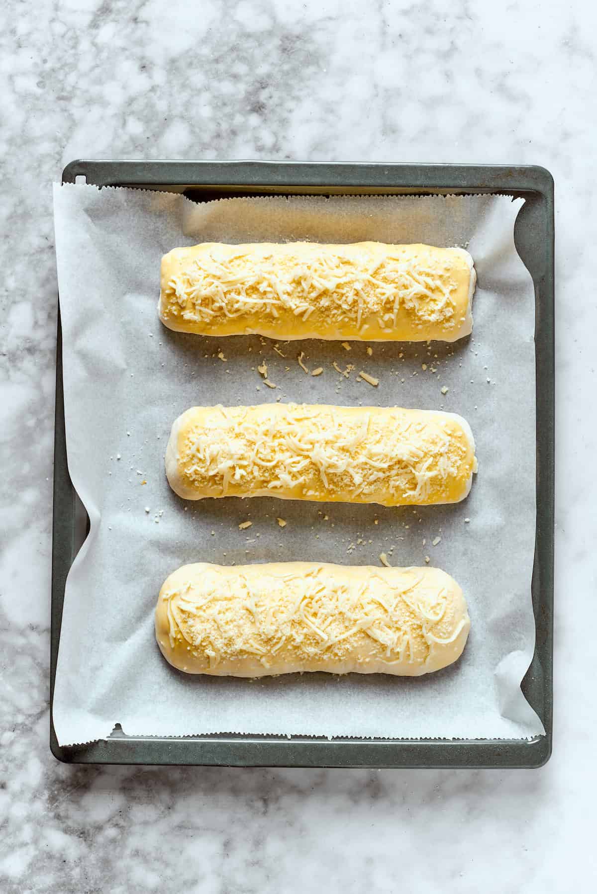 Three Costco chicken bake rolls on a baking sheet.