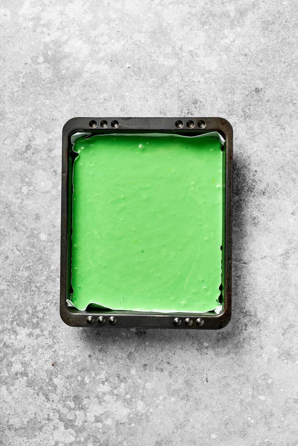 A square pan with green cake batter.