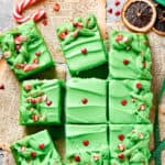 Twelve slices of grinch cake topped with candy on a counter.