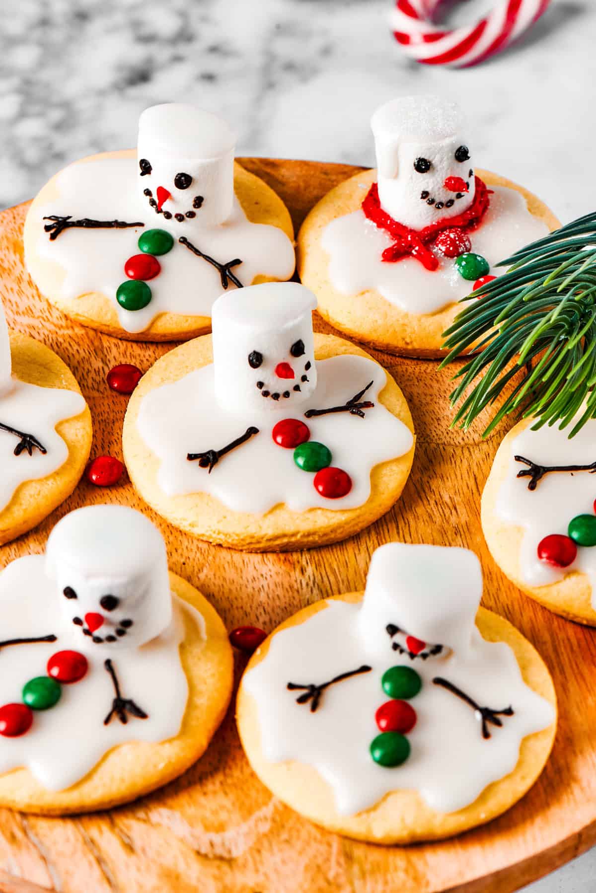 Melted snowman cookies on a wooden tray.