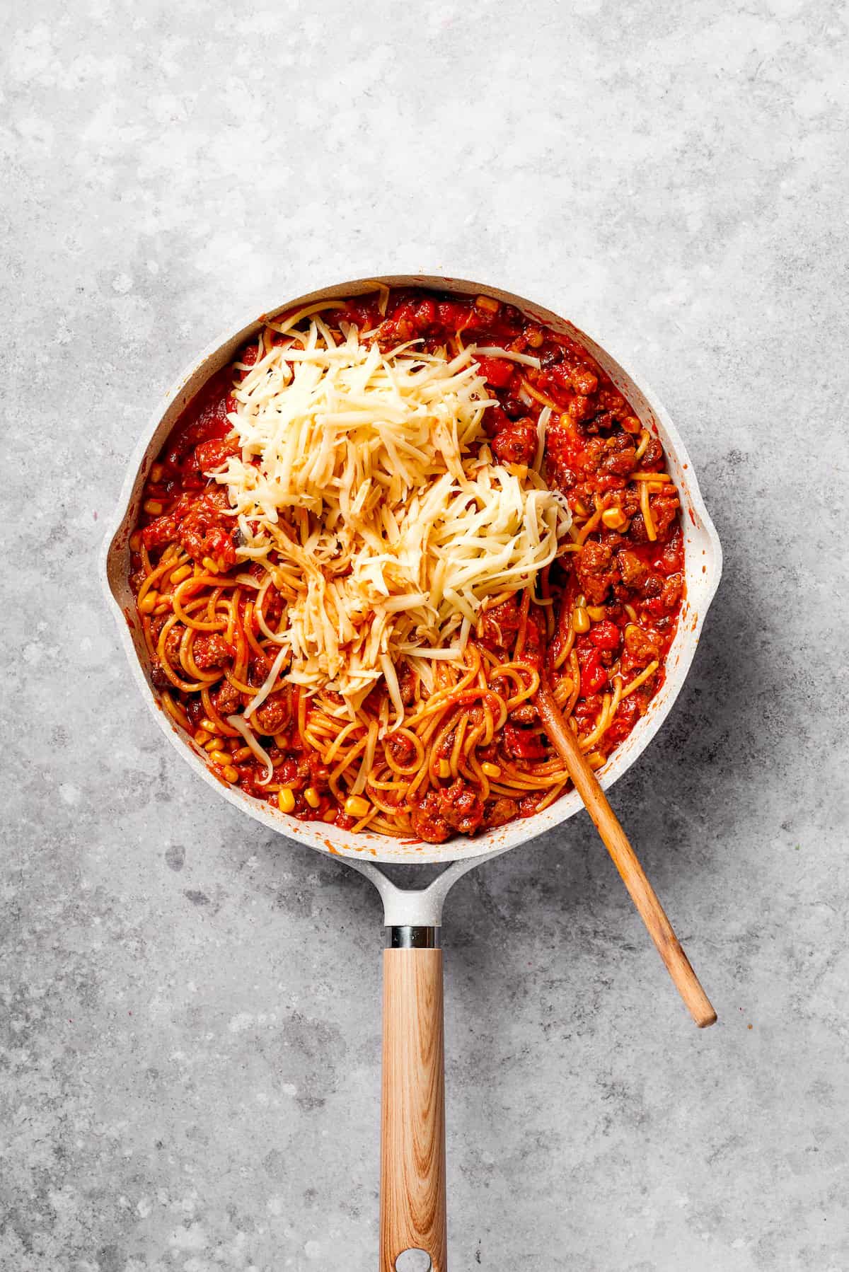 Cheeses are mixed into a pan of Mexican spaghetti.