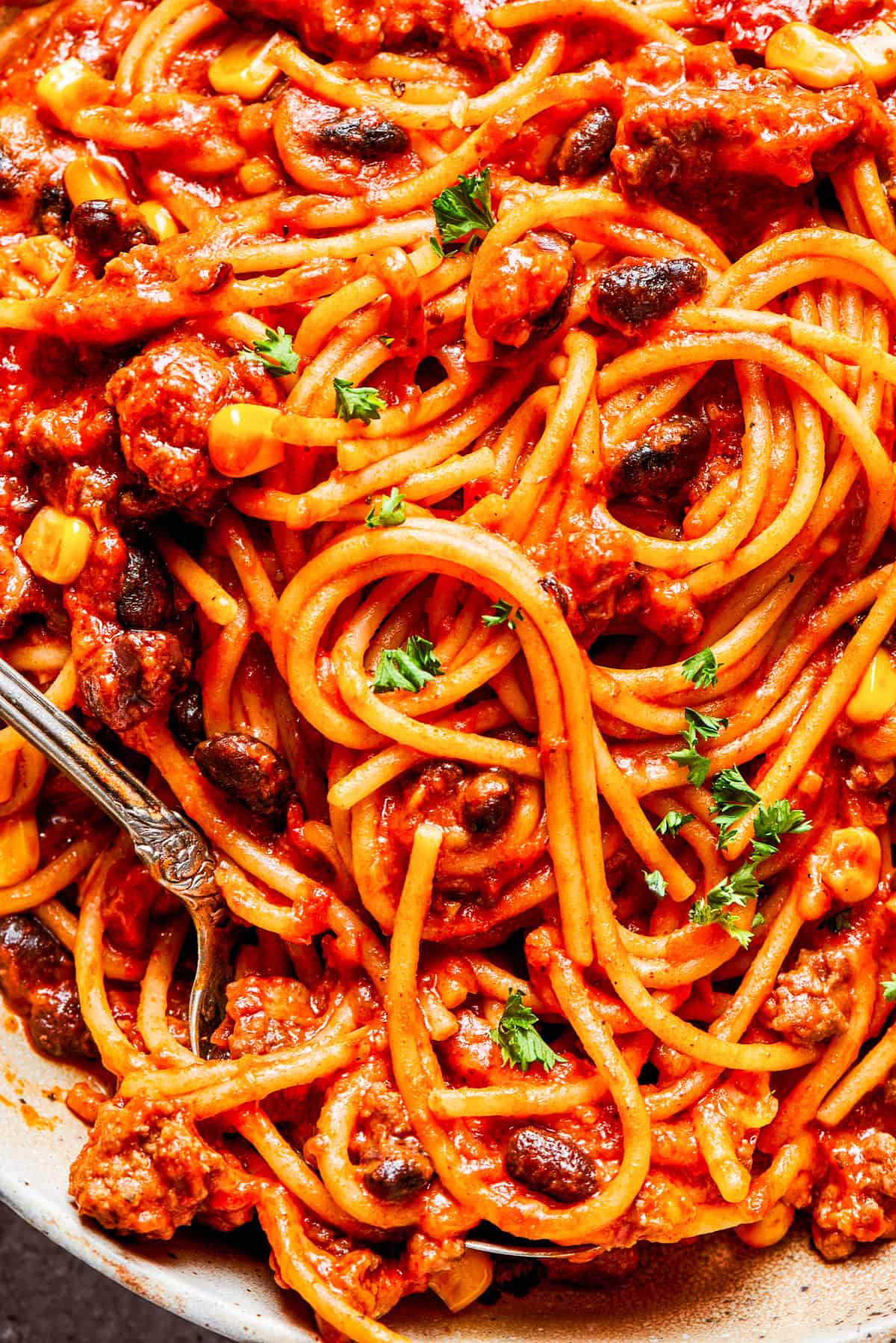 Close-up image of cooked Mexican spaghetti tossed with tomato sauce and beans.