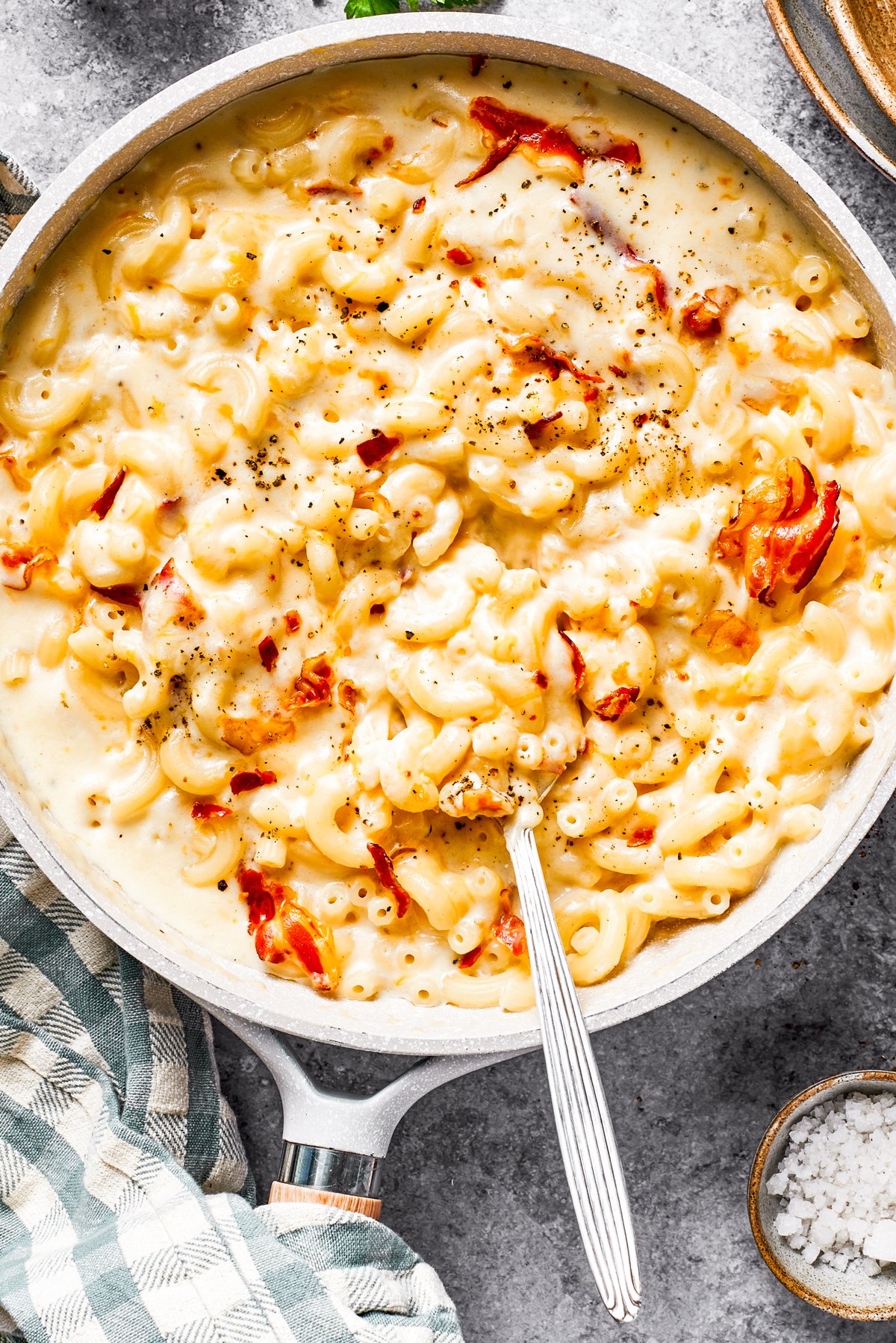 A skillet with mac and cheese and bacon stirred in.