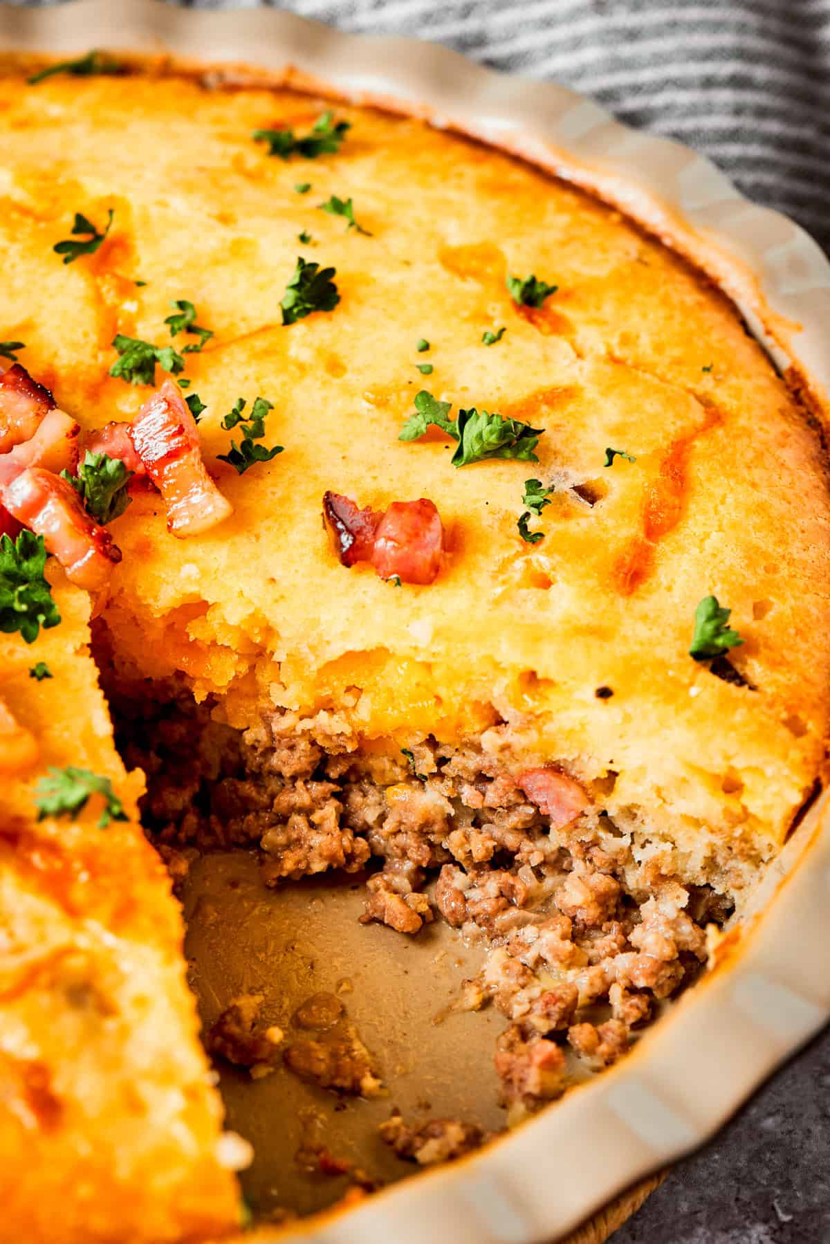 Close-up photo of a cheeseburger pie with a piece of pie cut out to expose the ground meat.