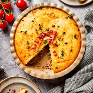 Overhead image of cheeseburger pie in a pie dish, with one wedge cut out.