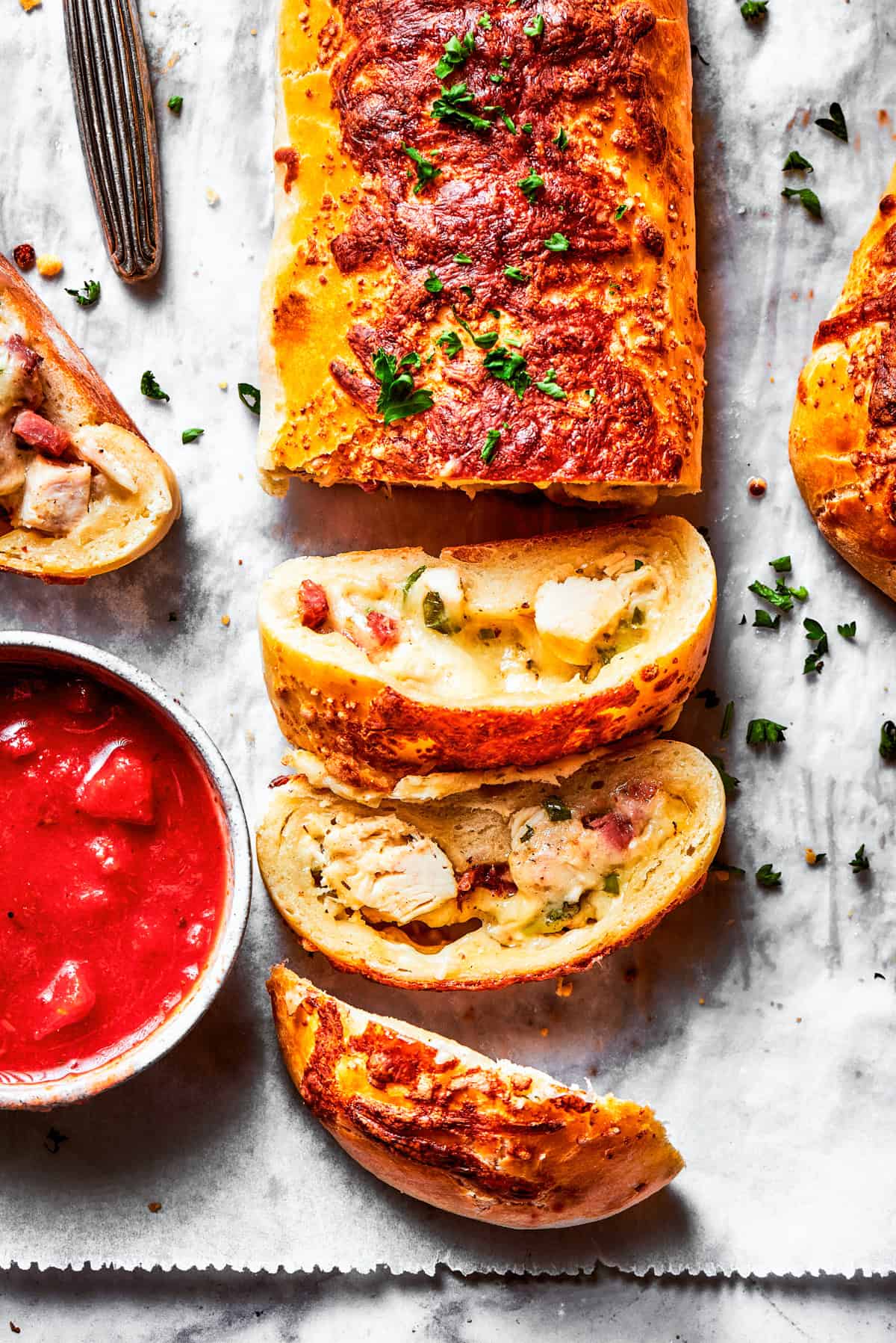 A sliced Costco chicken bake and a bowl of sauce.