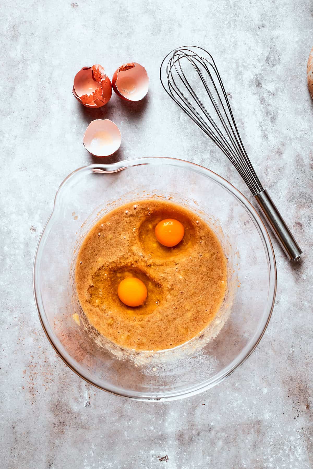 Two eggs are added to banana bread batter.