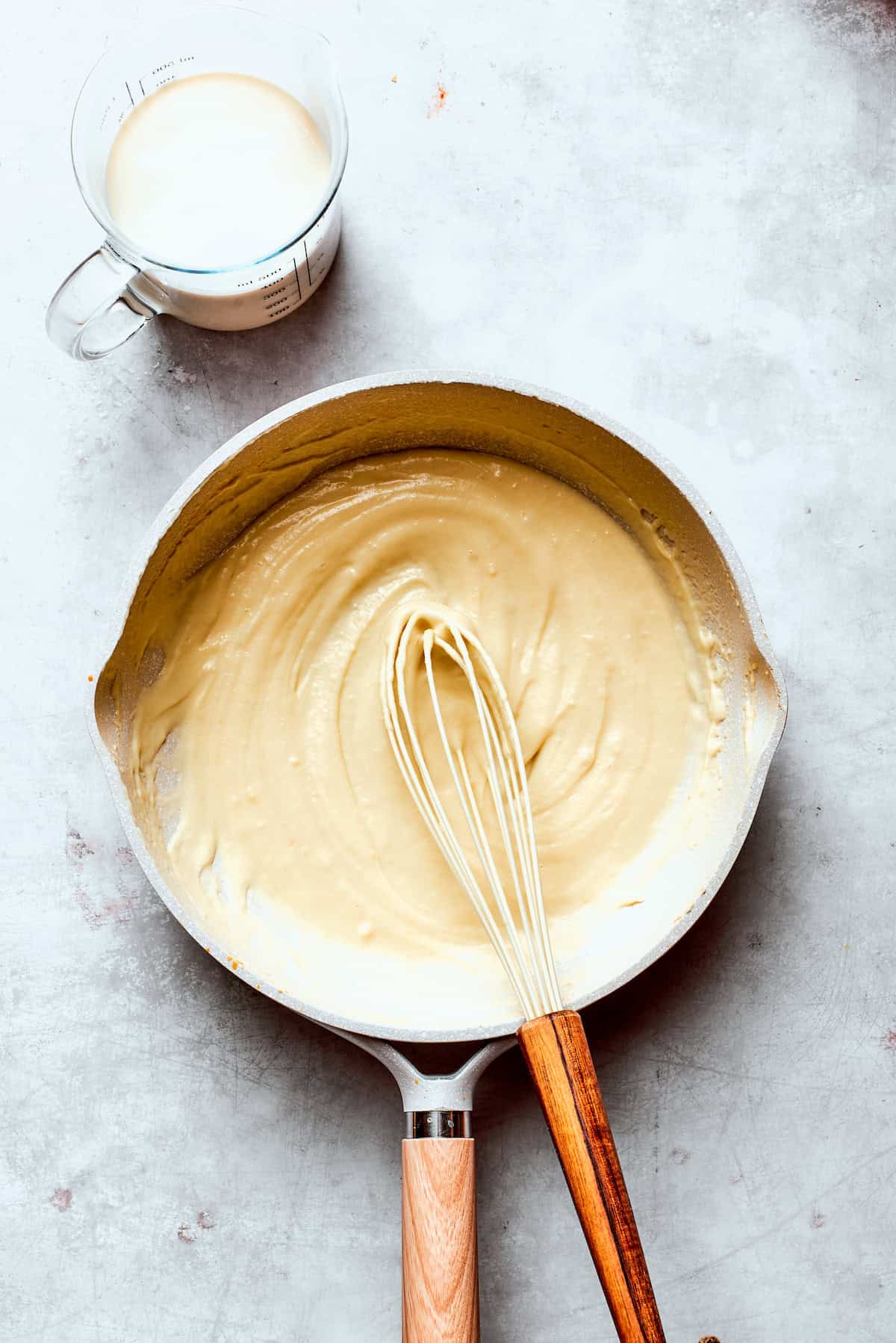 Milk is whisked into a skillet of roux.