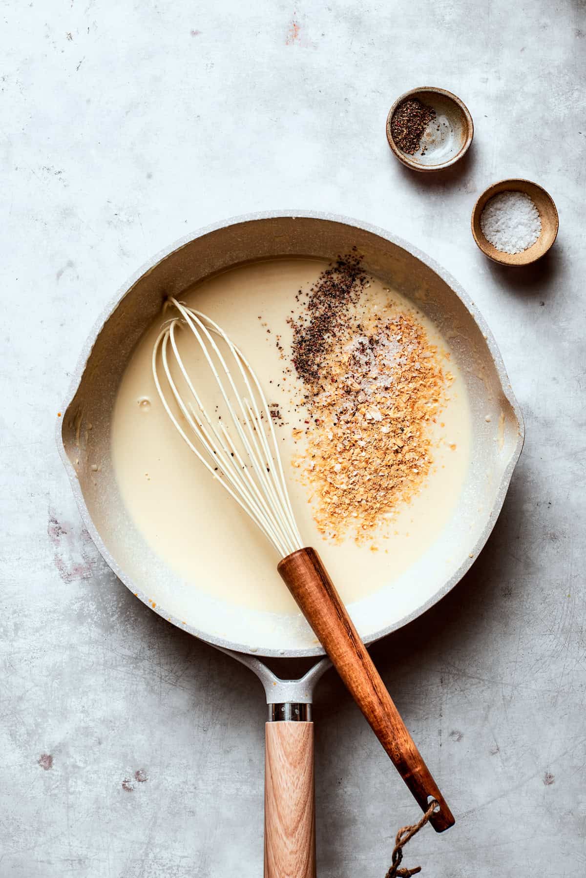 Seasonings are added to gravy in a skillet.