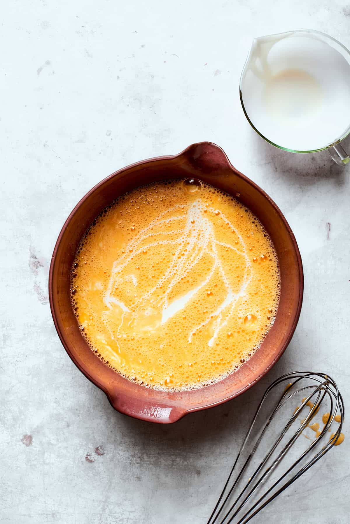 Eggs whisked with cream in a bowl.