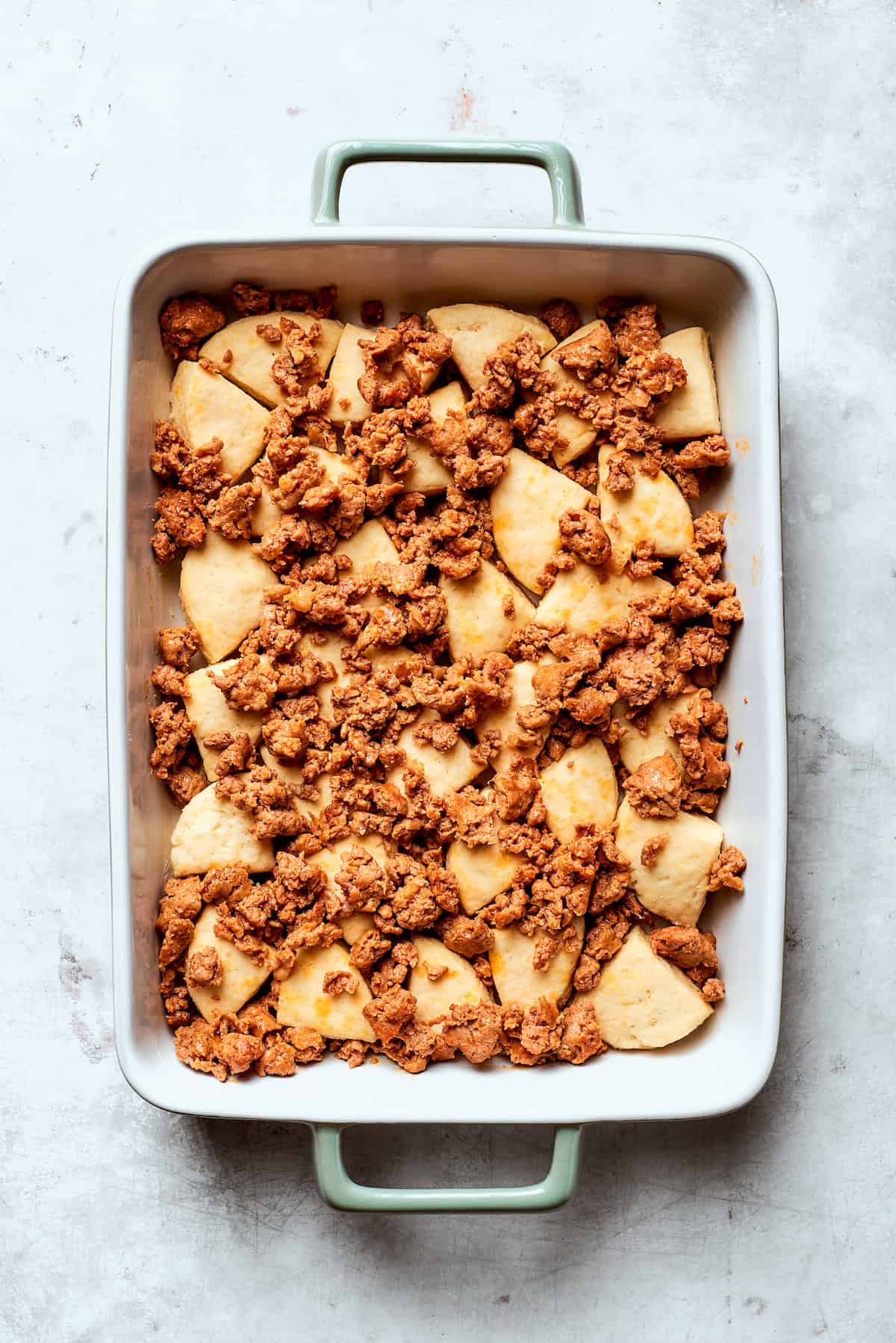 Browned sausage placed on top of biscuit dough pieces.