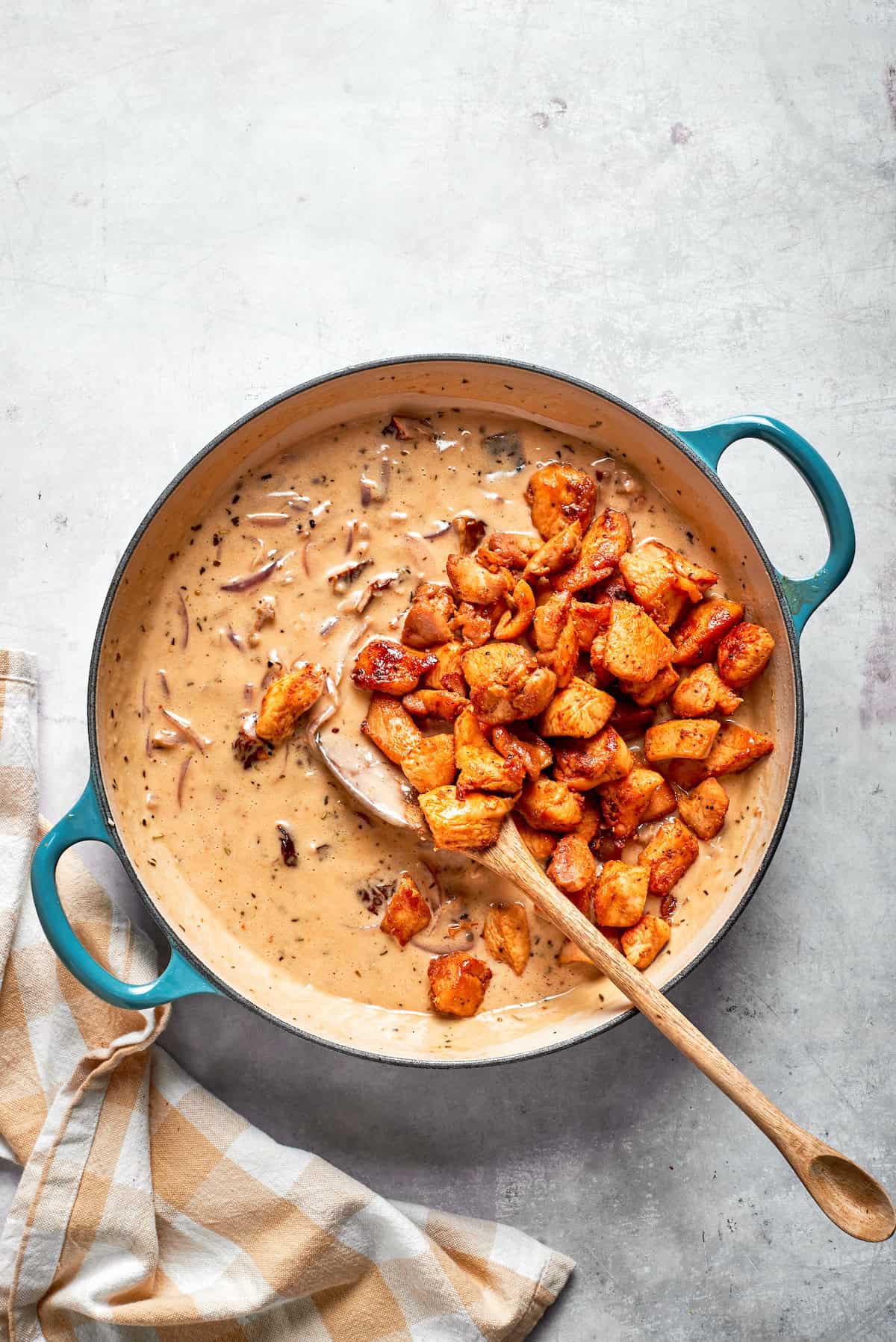 Cooked chicken added back to a skillet of cream sauce.