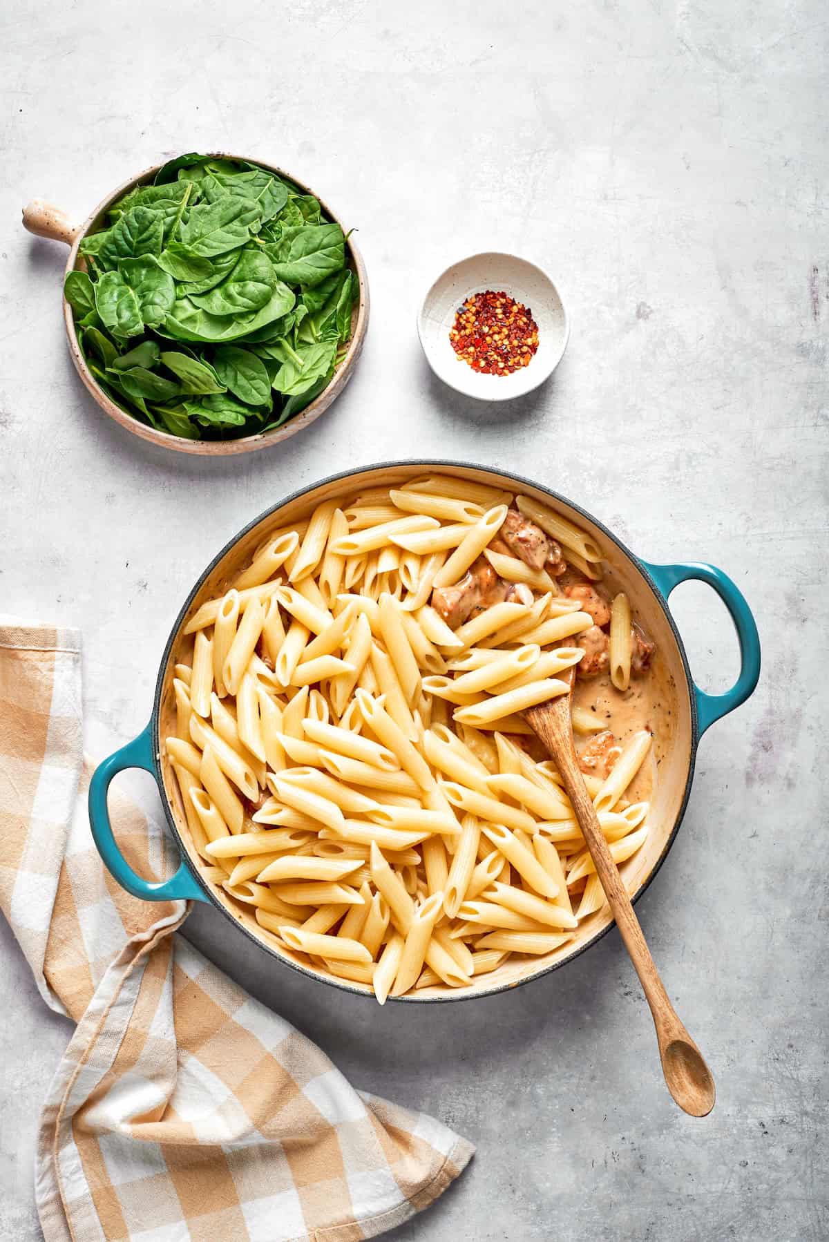 Pasta is stirred into cream sauce in a skillet.