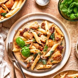 A plate of marry me chicken pasta garnished with fresh basil.