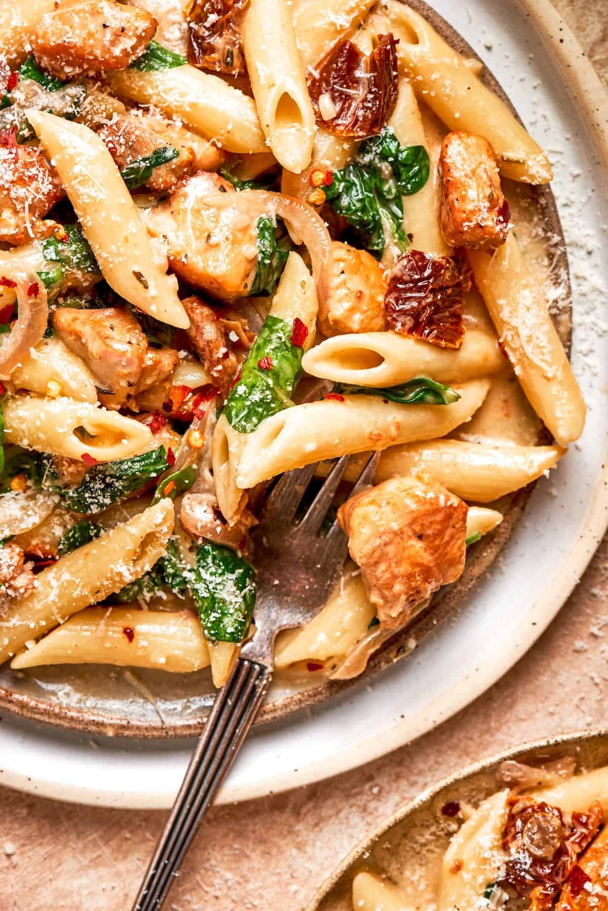 A fork rests in a plate of marry me chicken pasta.