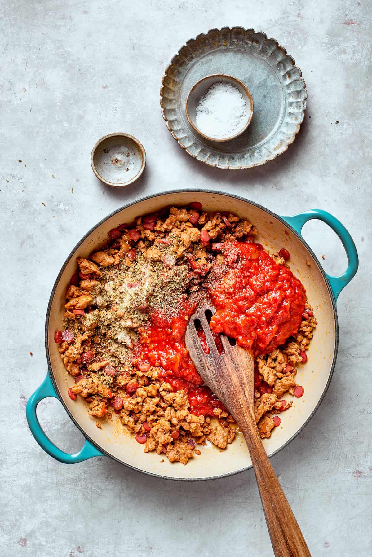 Tomato sauce is stirred into a pan.