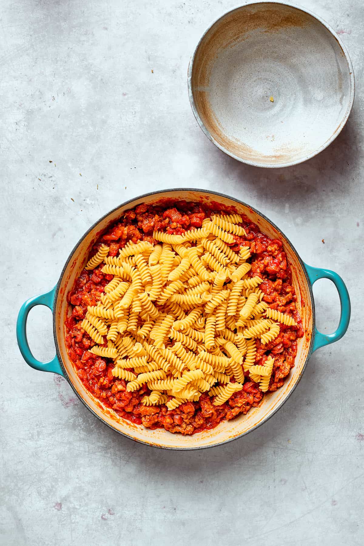 Pasta is added to a pan of sauce.