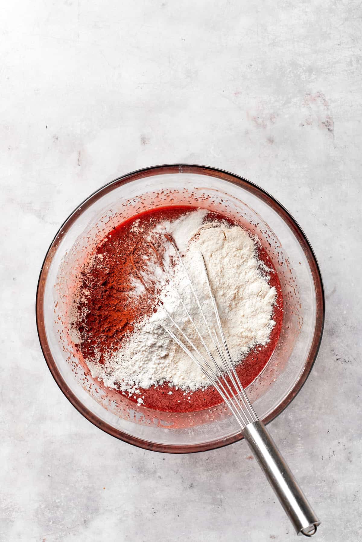 Flour is whisked into red velvet brownie batter.