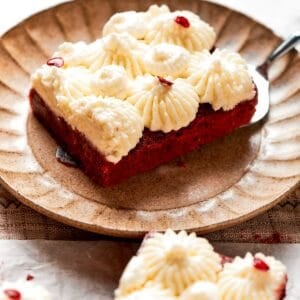 A red velvet brownie with frosting on a plate.