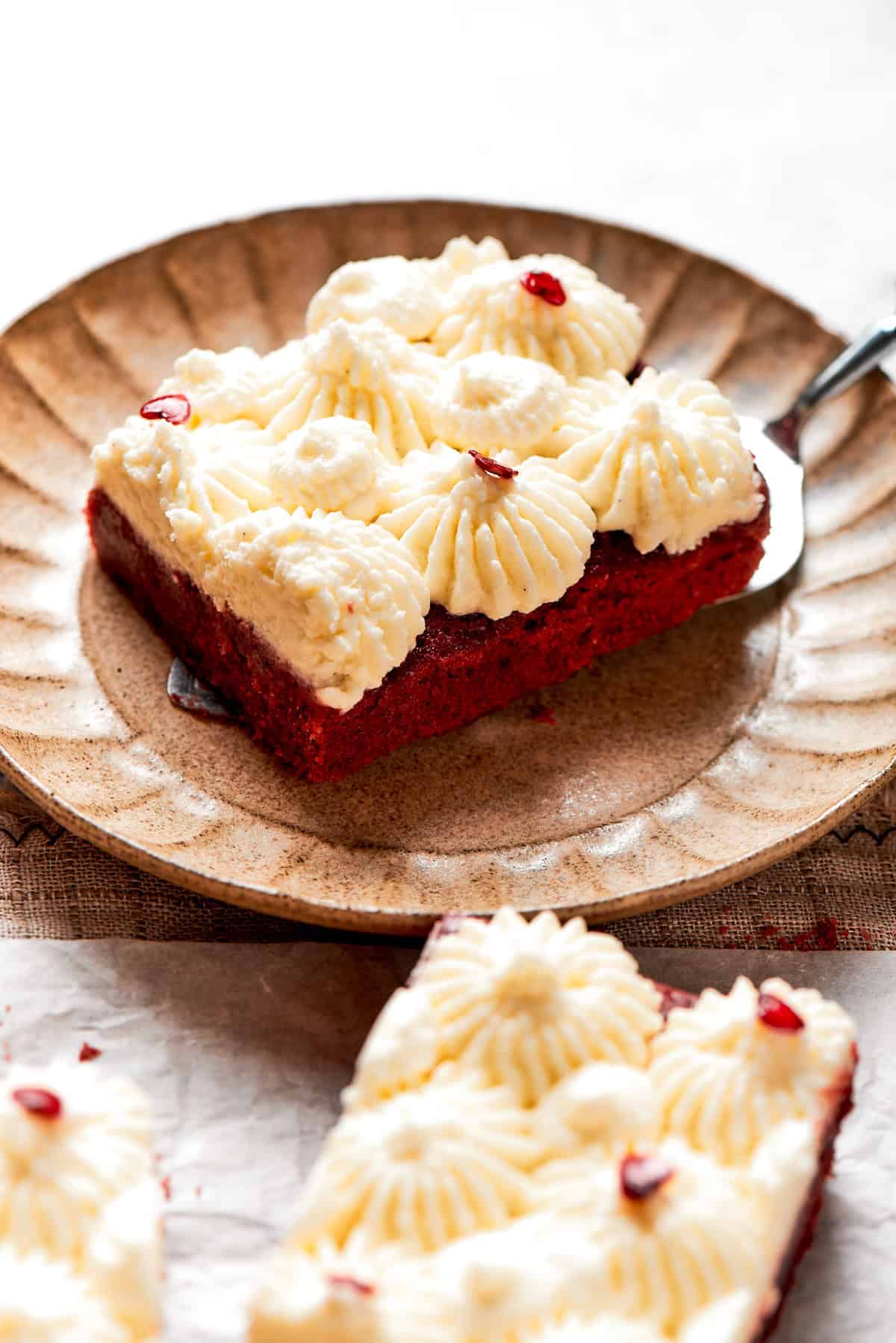 A red velvet brownie with frosting on a plate.