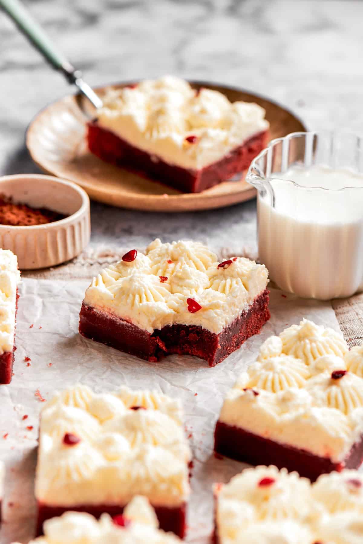 A red velvet brownie with a bite taken out and a glass of milk.