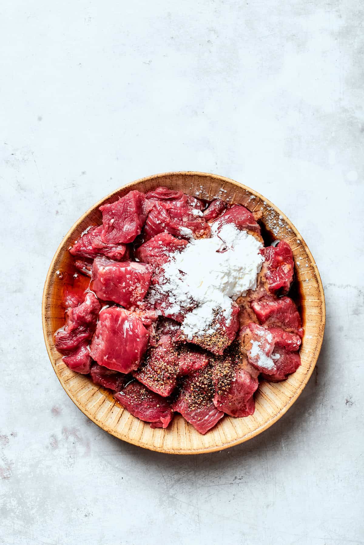 Cubes of steak are mixed with cornstarch and baking soda.