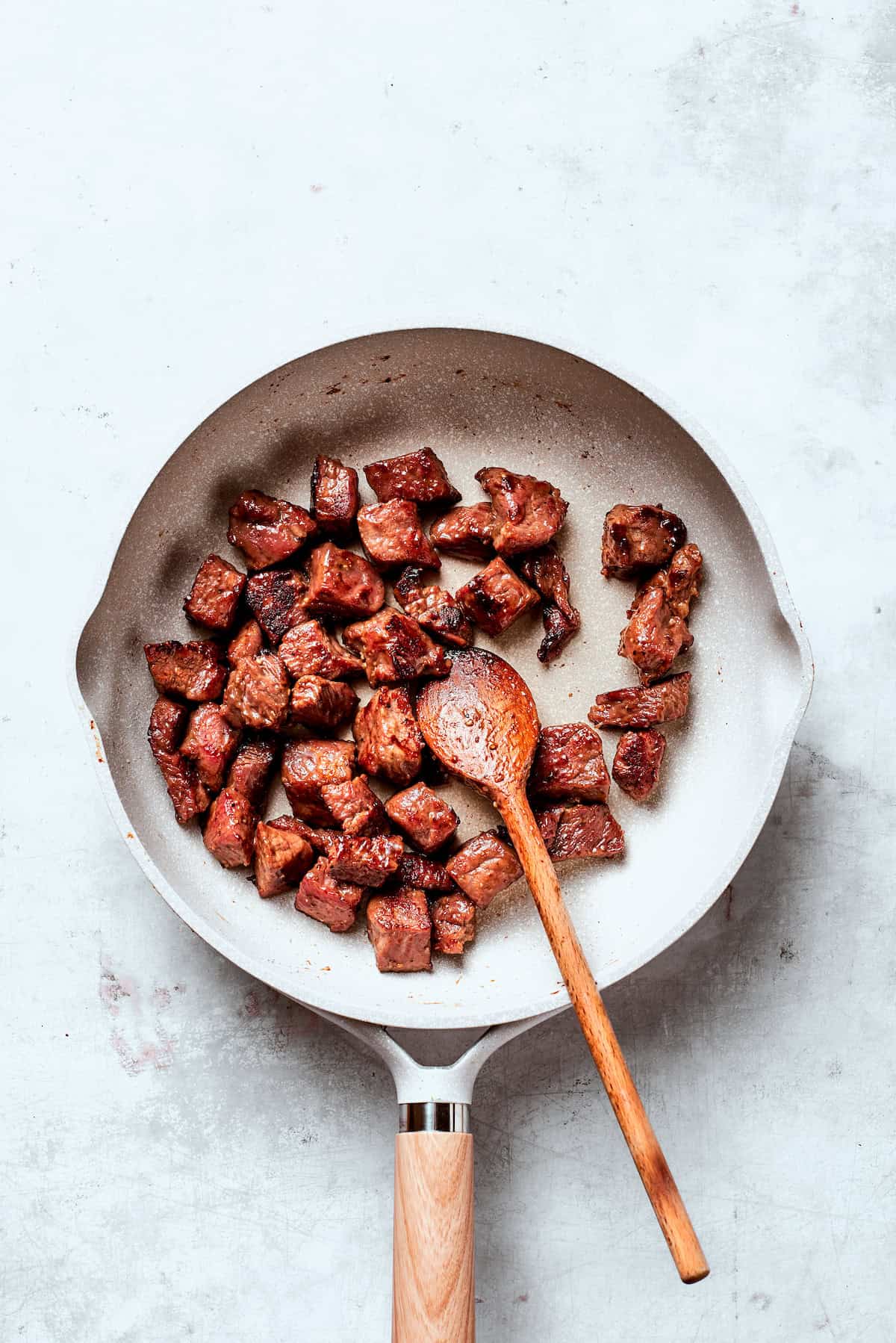 Cubes of steak cooked in a pan.