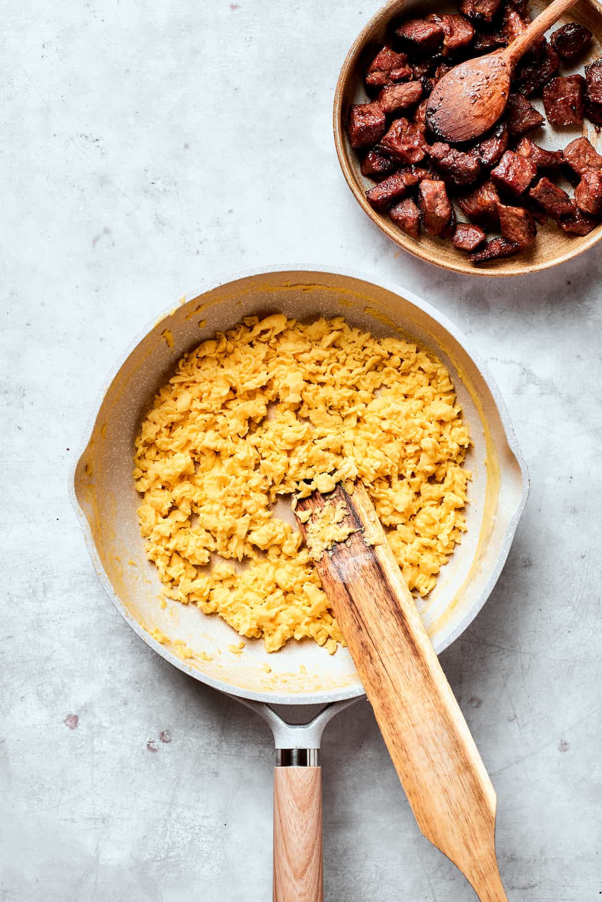 Eggs are stirred as they cook in a pan.