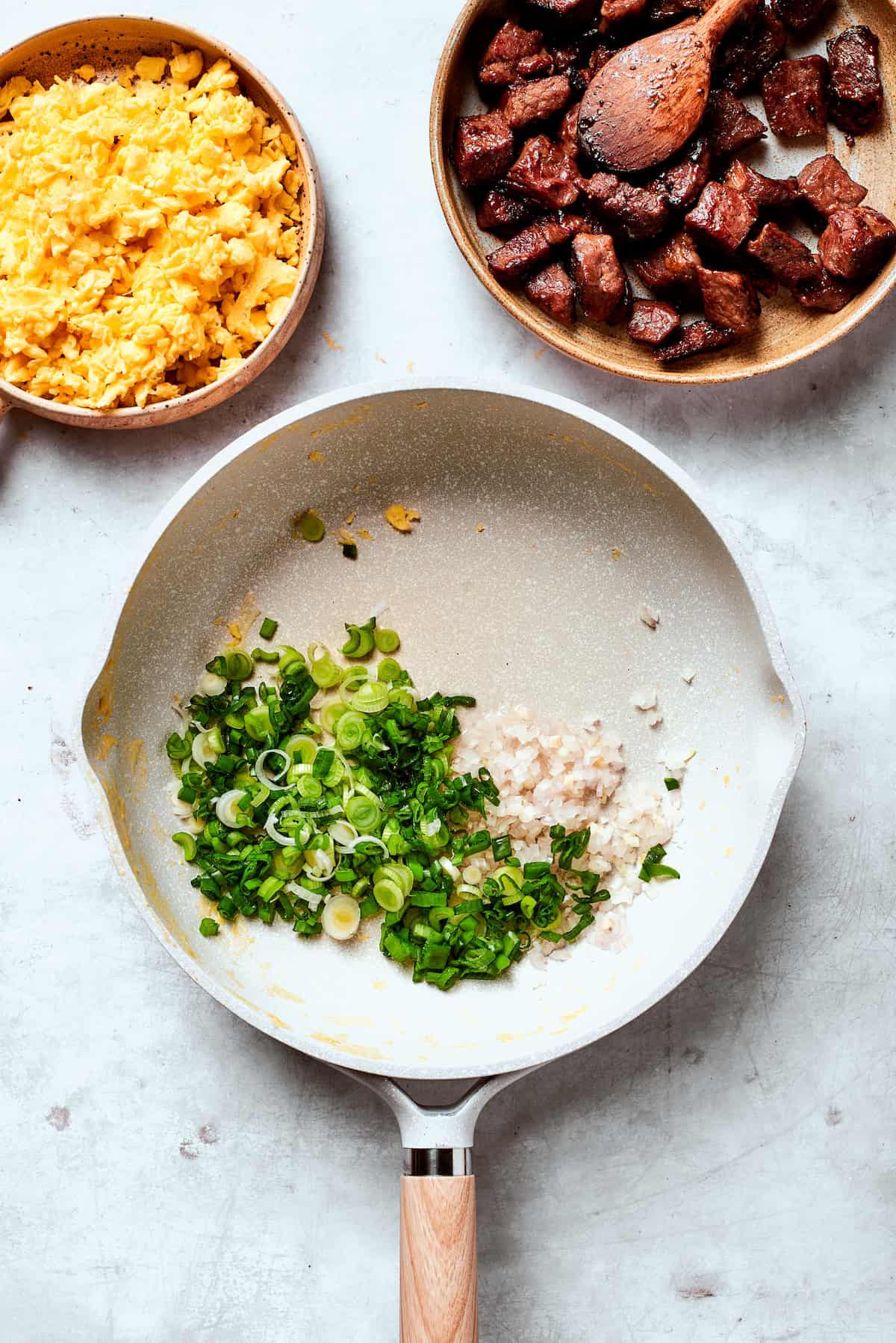 Scallions are cooked with garlic in a pan.