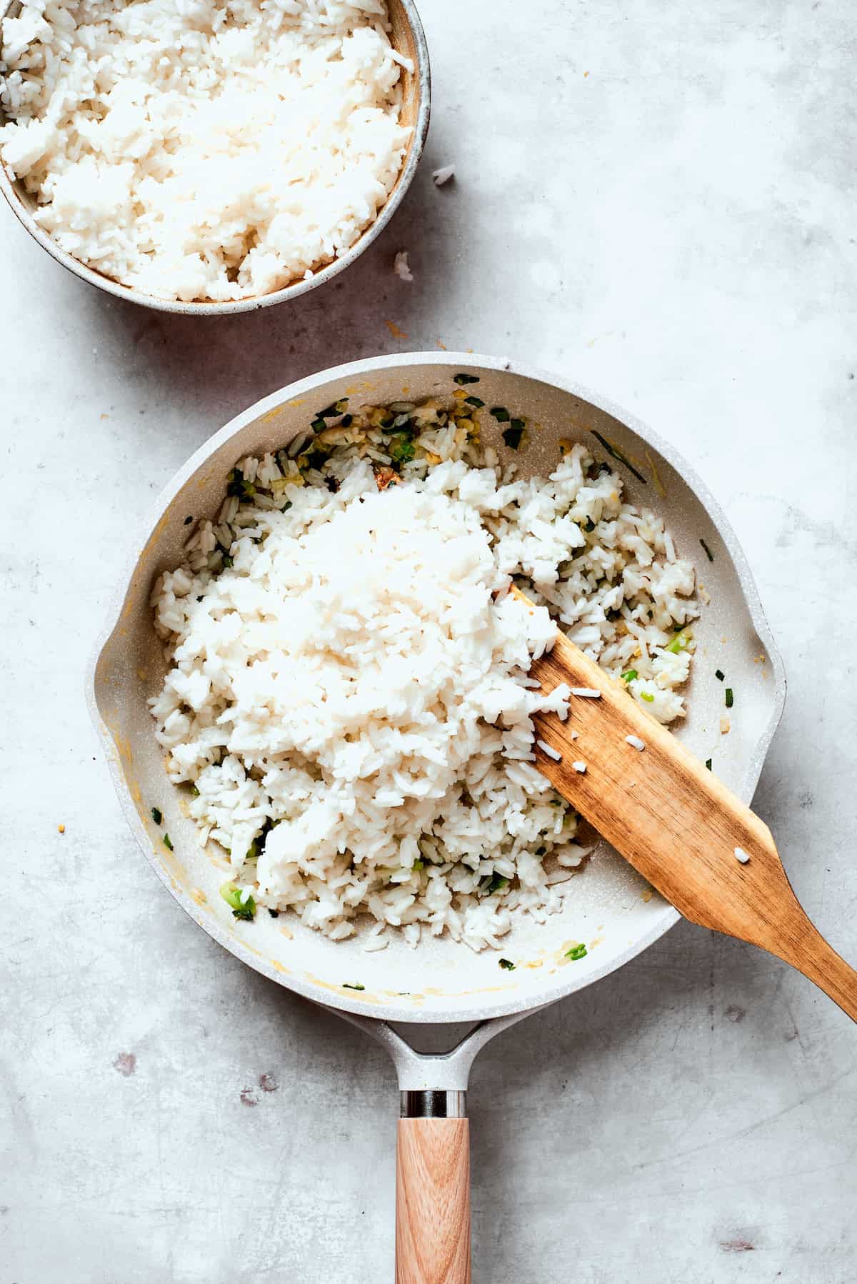 White rice is stirred into a pan for fried rice.