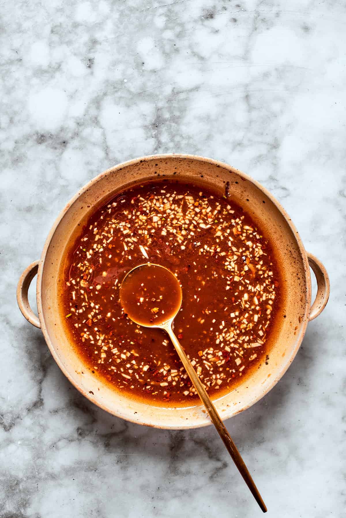 A spoon in a bowl of teriyaki sauce.