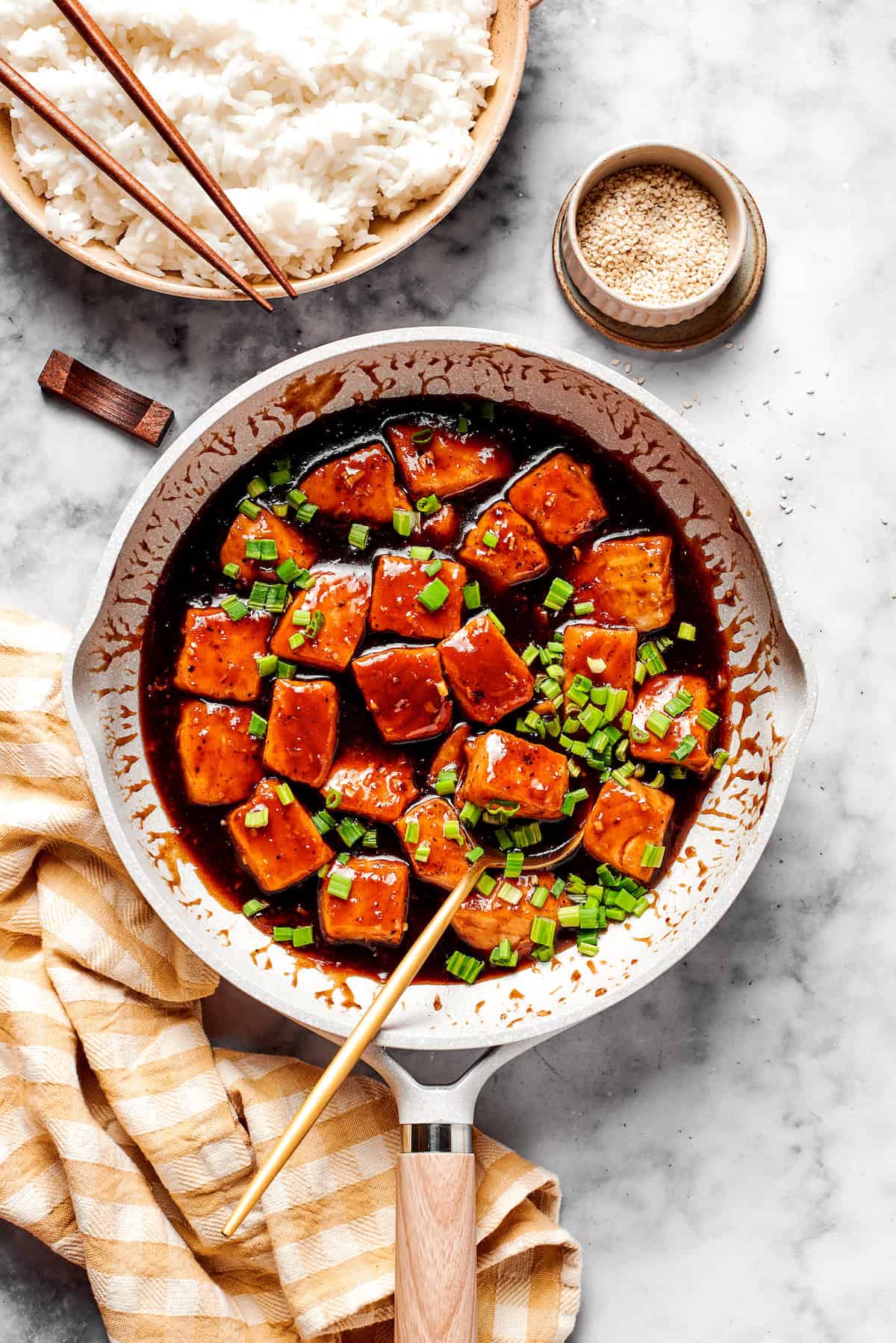 A skillet of teriyaki salmon and a bowl of rice.