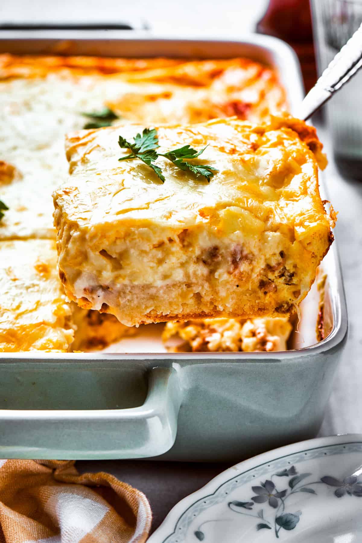 Lifting up a slice of biscuits and gravy casserole from a baking dish.