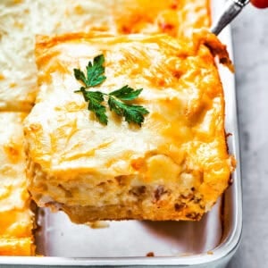 Scooping out a slice of casserole from the baking dish.