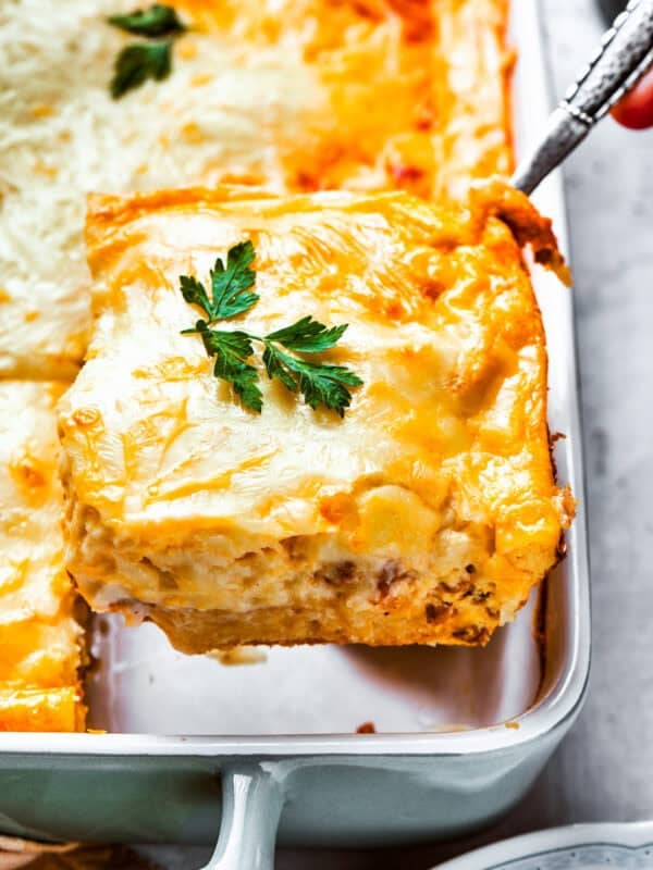 Scooping out a slice of casserole from the baking dish.